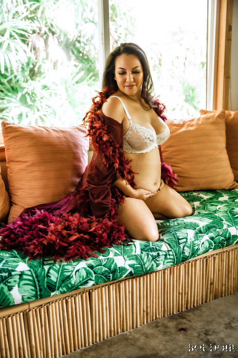 Smiling woman wears white lace lingerie set while cradling pregnant belly