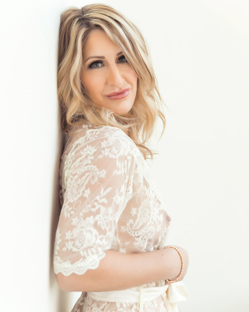 Woman posing in a lace white robe during a boudoir photoshoot